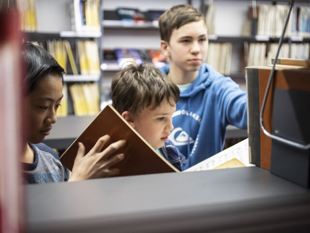 Bild von Jungen in der Bücherei vor einem Bücherregal